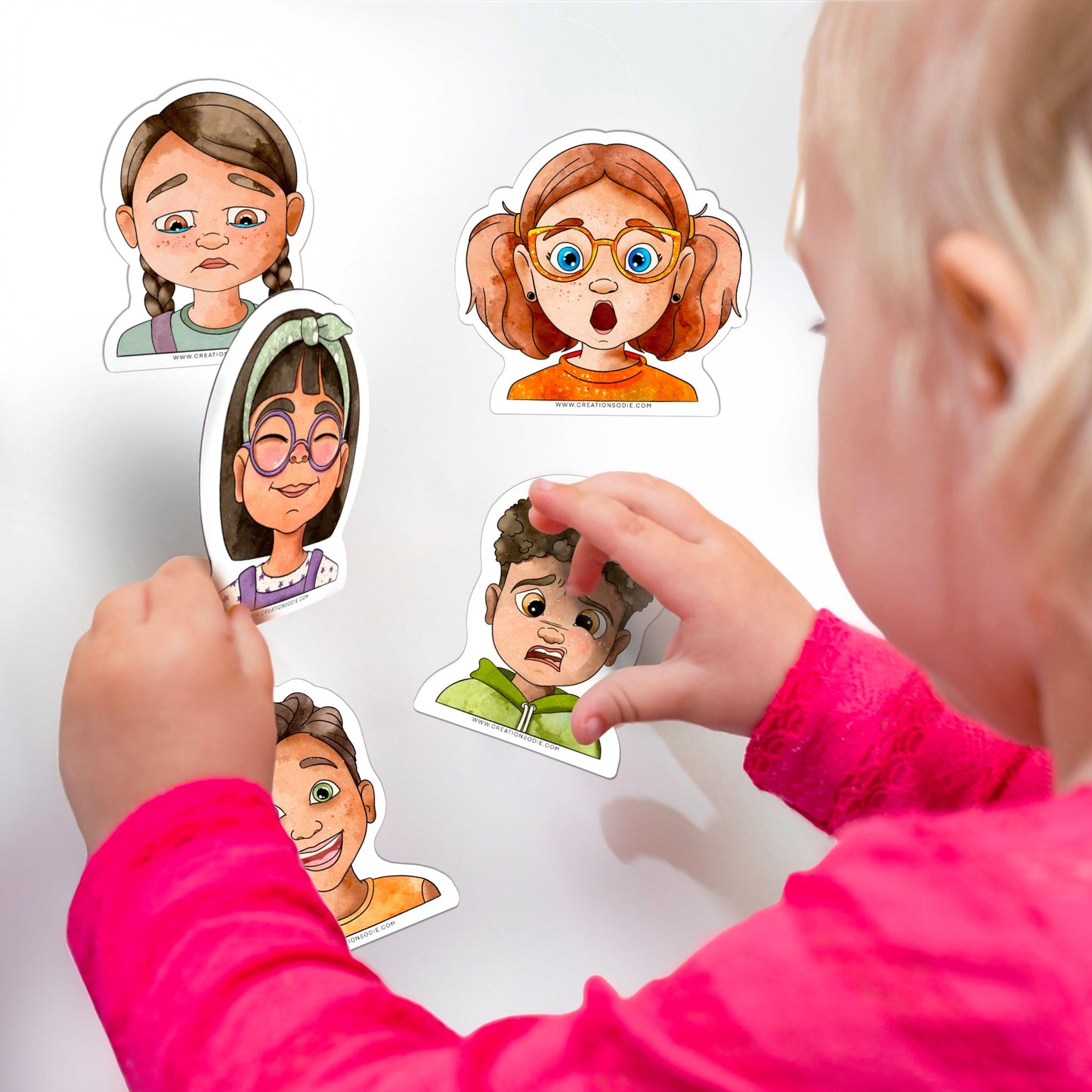 Gros plan d'un enfant manipulant les aimants d'émotions sur une surface magnétique