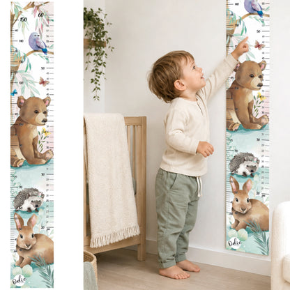 Une enfant regarde son échelle de croissance collé au mur de sa chambre. ce sont des animaux de la foret comme thématique, ours, oiseau, lapin et hérisson