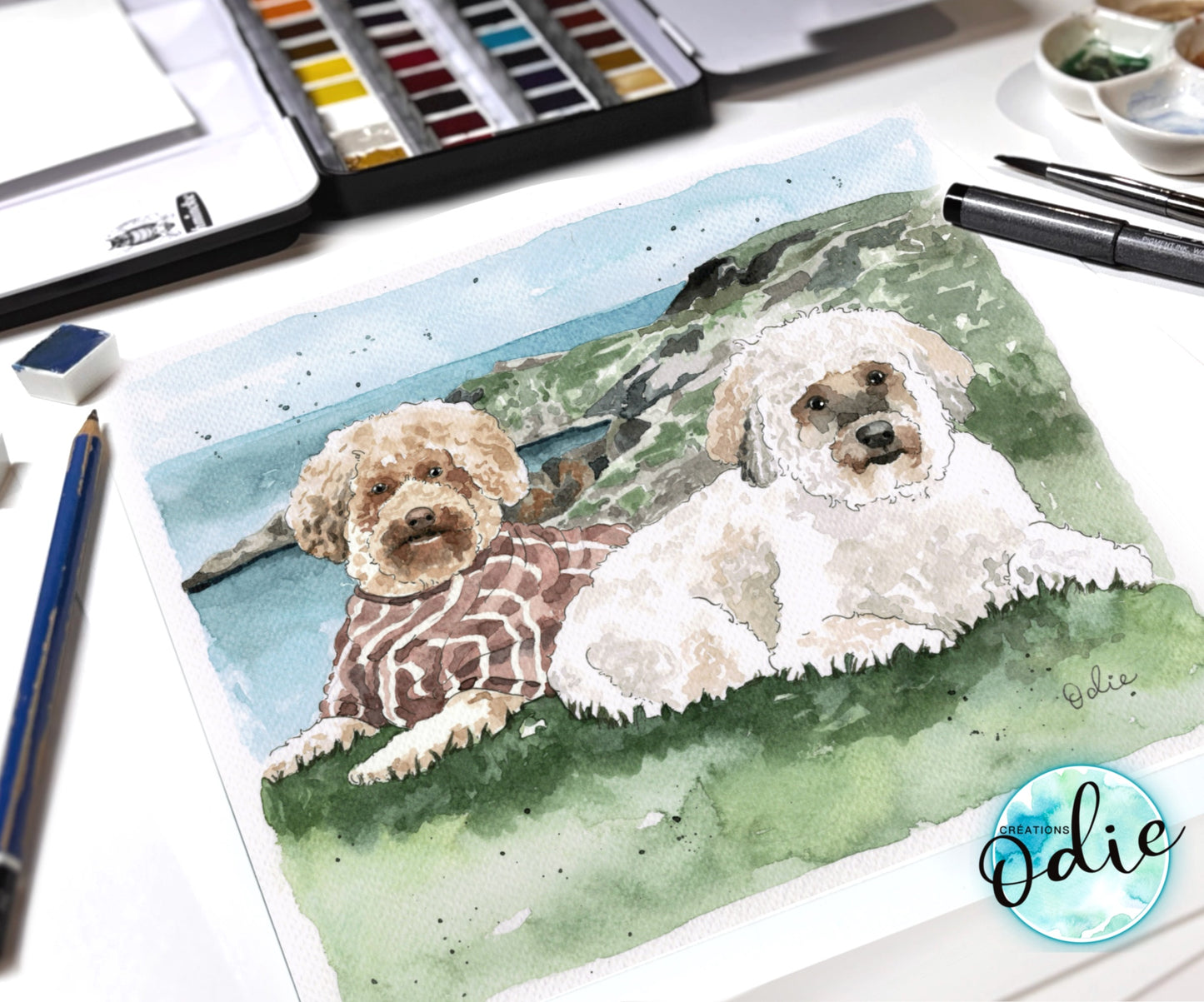Une aquarelle de deux chiens peints a la main déposer sur une table de travail avec des crayons et pinceaux