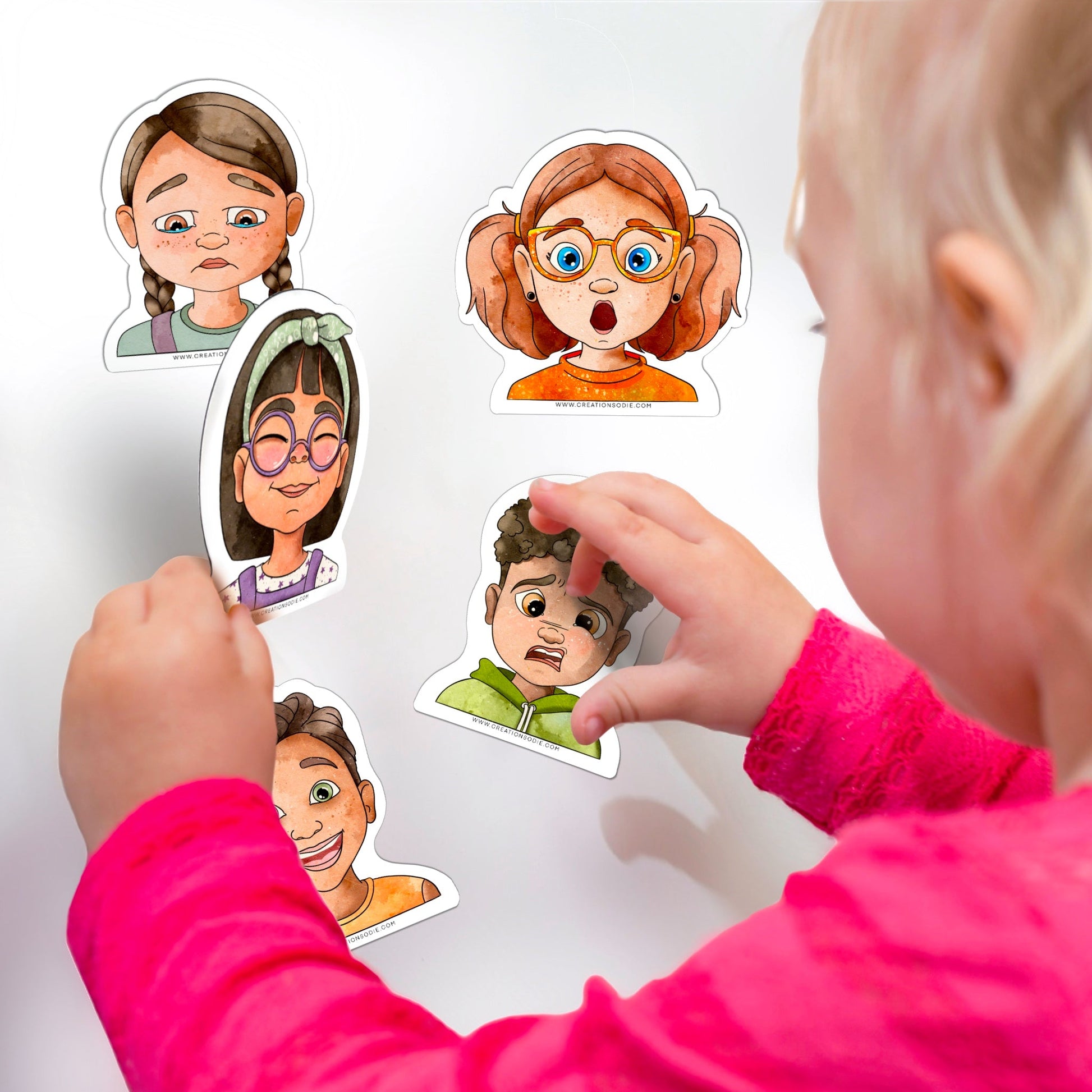 Gros plan d'un enfant manipulant les aimants d'émotions sur une surface magnétique