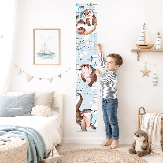 Un petit garcon qui prend sa mesure de grandeur sur une échelle de croissance pour enfant avec de petites loutres des mers dans sa chambre. 