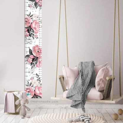 Échelle de croissance aquarelle roses et feuillage noir, installée dans une chambre d'enfant au décor doux